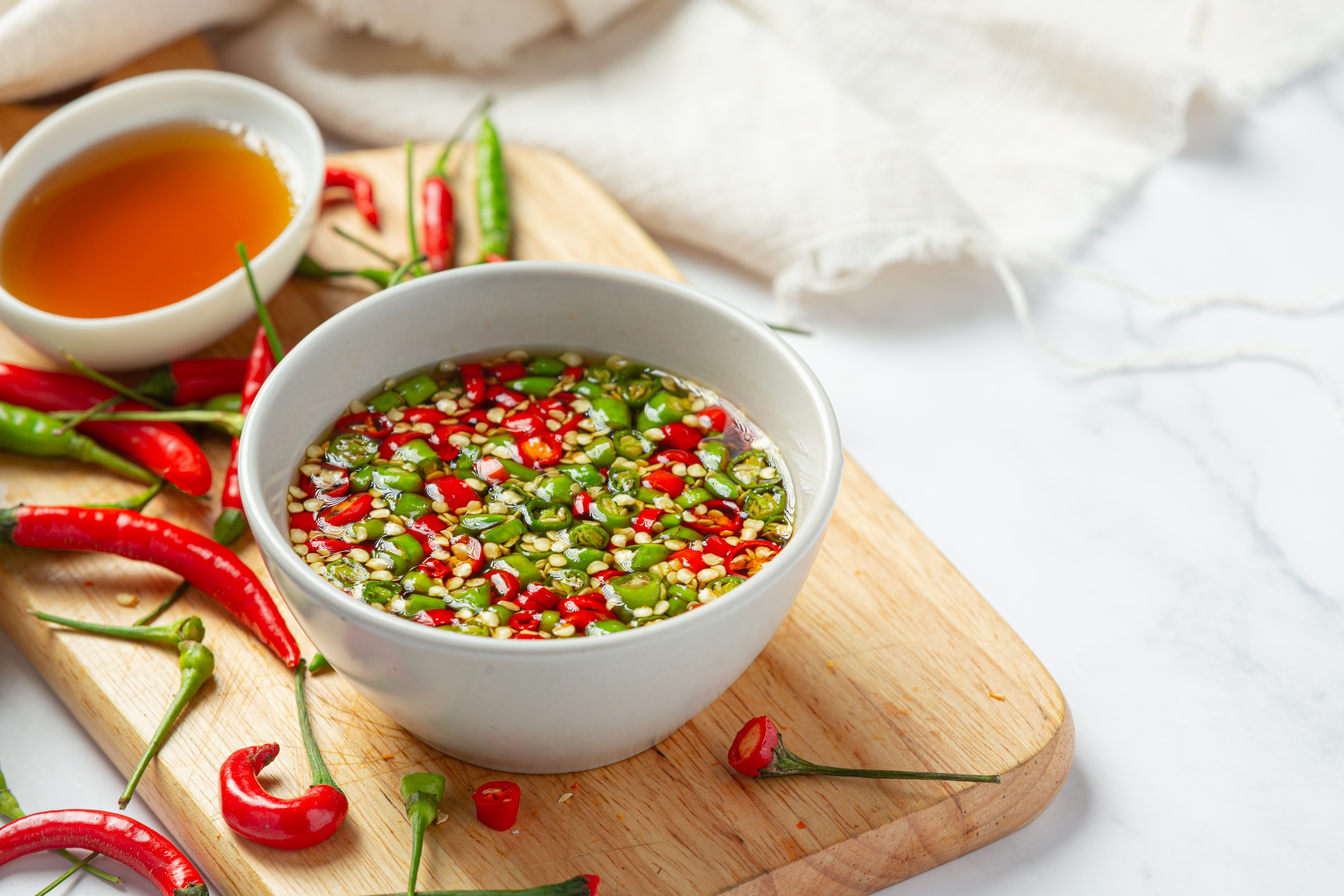 Thai Chili Fish Sauce Recipe That Keeps Chilies from Turning Black: Chilies darken due to oxidation. Once sliced, the inner flesh is exposed to air, causing its natural pigments to change from vibrant green or red to a darker brown. In addition, the chilies' natural enzymes and plant compounds react with the salt in the fish sauce, accelerating discoloration and causing the chilies to soften and darken more quickly.